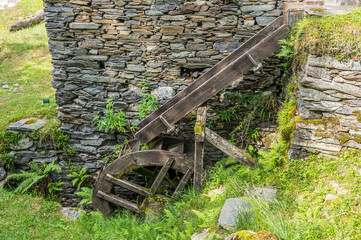 Stone watermill with wooden wheel in an abandoned mountain village in the Alps