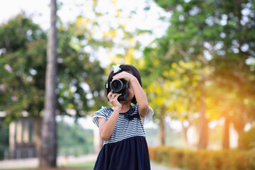 Asian little girl playing with toy camera in the park.