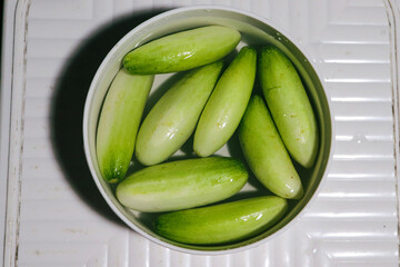 Vegetables soaked in water, cucumbers soaked in water to reduce toxic residues. In a white container and flood the cucumbers.,green peas