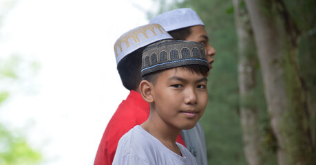 Portrait asian muslim or islamic boys standing together in front of tree and waiting to do the...