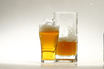 Foaming mug of beer in a glass against a white background