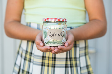Faceless kid showing jar with dollars