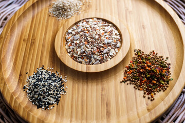 Mixture of spices for baking on a wooden plate. Includes flax sesame and sunflower seeds