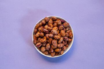 Kidney beans in bowl. Top view of raw kidney beans isolated on purple background.