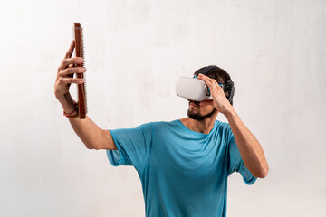 Young man using virtual reality headset. Holds in hands a board for standing on nails on a light background