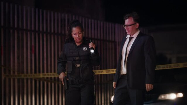 Detective Arriving at Crime Scene at Night and Greeted by a Black Policewoman. Police Officer Briefing Inspector on Evidence Found Near the Victim's Body. Forensics Experts and Policemen Working