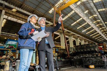 A business man inspects the work of an on-site worker at an old factory for rehearsing train engines.