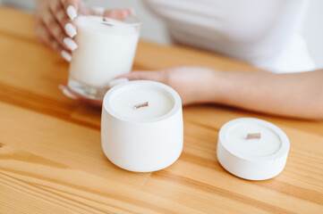Place Under Label on Soy White Candles. Group of White Candles Stand on Wooden Table. Women's h\Hands with Ring Hold Candle Close-up
