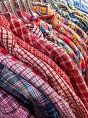 Many colorful checkered formal shirts hanging on a racks