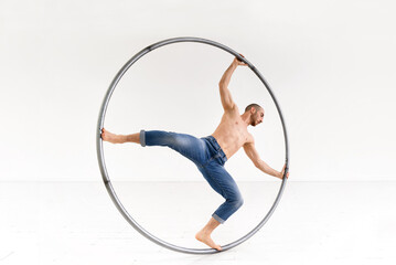 Shirtless man spinning on Cyr wheel