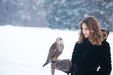 A girl holds a falcon on her hand