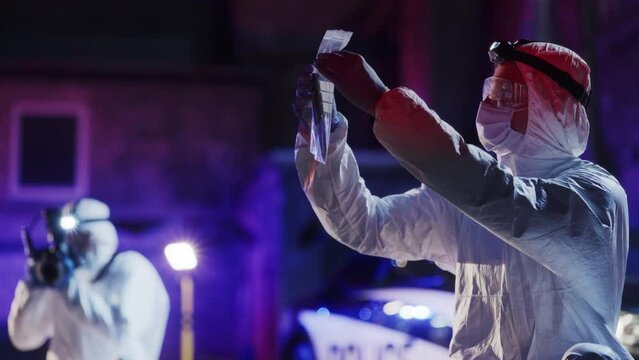 Tracking Shot: Forensics Specialist Checking Evidence Under Clear Lights, Then Putting the Bag in a Secured Case. Expert Considering Blood Pattern on a Murder Weapon Before Sending it for DNA Analysis