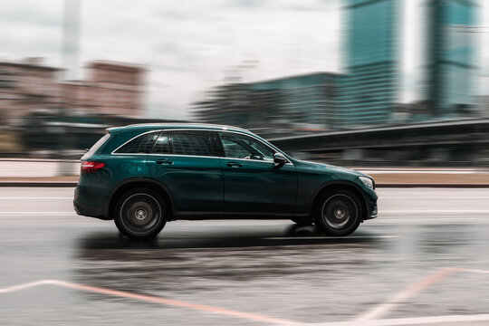 Mercedes-AMG GLC 43 On The Road In Motion. Fast Speed Drive On City Road. Side View Of Moving Green Car On The Street