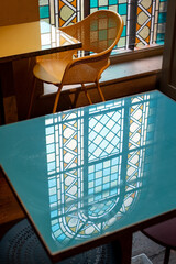 Stained glass windows let light into a cafe in a deconsecrated, restored church in Mayfair, London, UK. Light reflects off the glass table. Photo represents the decline in religion in modern society.