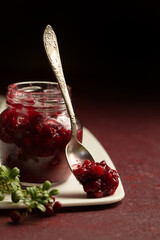 lingonberry sauce in a glass jar on a burgundy background