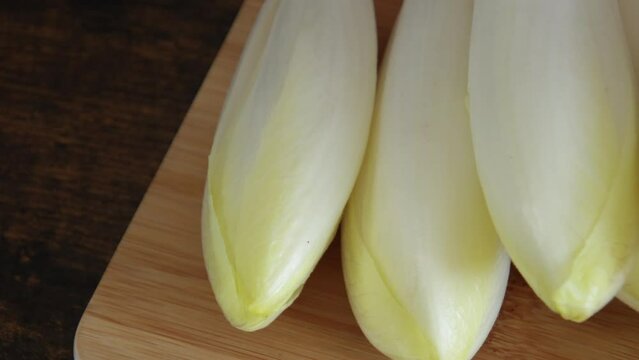 tas d'endives crus sur une planche &agrave; d&eacute;couper