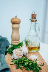garlic, greens, salt on a wooden board, oil and a pepper mill. ingredients for health	
