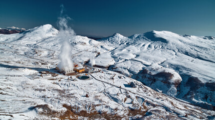 Aerial view to geothermal power plant in mountain. Clean green renewable energy in Kamchatka. - 550634124