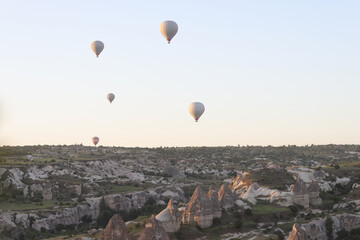 Hot air balloons fly in the evening sunset sky over Goreme National Park.