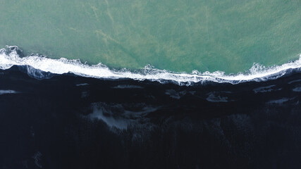Aerial shot of black beach in Iceland and Atlantic ocean, shot from the drone
