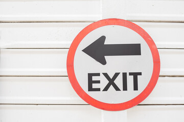Exit left sign with a cement wall white background.