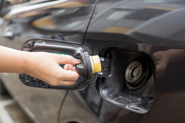 Closeup of a woman opening fuel tank grey car.