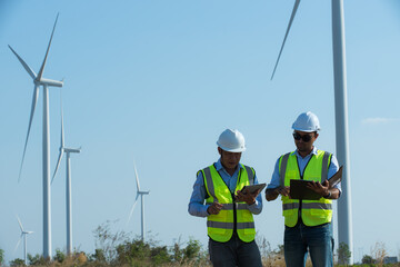 person with wind turbine in the field. two workers in the wind. person with wind turbine in the field. two engineers discussing against turbines on wind turbine farm.