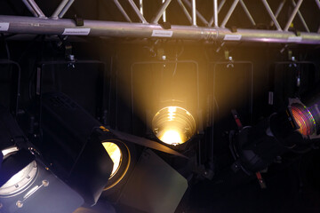 Professional lighting fixtures are suspended on a pole above the stage and shine with cold light.