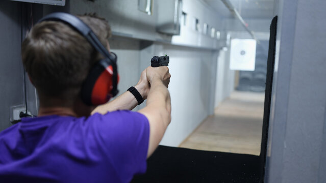 Man shoots at target with pistol in shooting range.