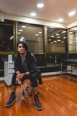 Handsome and serious young model with long hair seated in a big office in the night