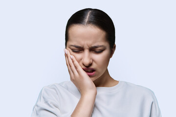 Fototapeta premium Teenage girl having toothache, on white studio background