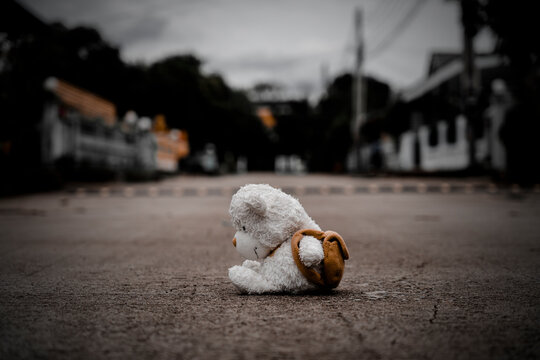 lonely teddy bear sleep on cement floor for created postcard  of international missing children, broken heart, lonely, sad, alone unwanted cute doll lost.