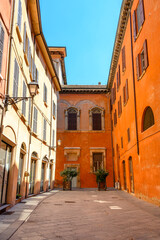 Small Italian rectangular yard with colorful house facades, with blue sky
