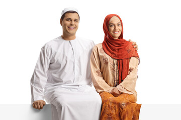 Young couple in ethnic clothing sitting on a white panel