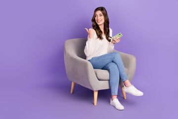 Photo of charming cute lady sit chair look empty pace demonstrates offer device shop banner isolated on purple color background