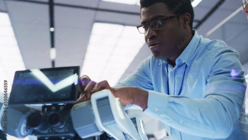 Poster Robotics Engineer Working with Screwdriver, Collaborating on a Mobile Robot Animal Project. Close Up of a Black Man Screwing In a Circuit Board. Young Team Developing an AI Robotic Dog.