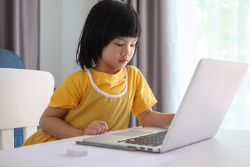 little asian girl student study online using laptop computer at home