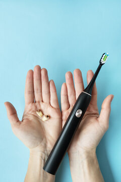 A modern electric toothbrush in one hand and pulled teeth in the other hand on a blue background. Hygiene concept of daily care of the oral cavity in order not to lose a tooth.