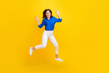 Fototapeta na wymiar Full length photo of shiny impressed girl dressed blue shirt jumping high empty space isolated yellow color background
