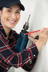 happy female worker using a pencil to mark a wall