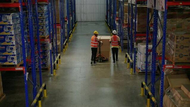 African American worker in a warehouse is using a cart to load boxes to be arranged in layers. warehousing, distribution, transport
