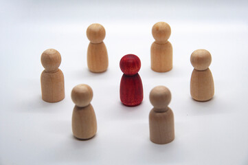 Red wooden doll surrounded with other wooden figure. leadership concept