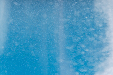 Background from falling blurry snow against blue sky.