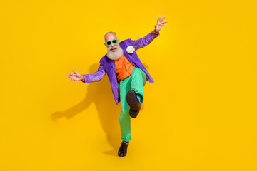 Full length photo of excited funky man wear purple velvet jacket having fun discotheque walking isolated yellow color background