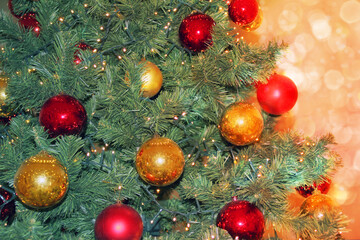 Obraz na płótnie Canvas green christmas tree with red and yellow balls, with lights and highlights, festive concept, form for greeting card, copy space