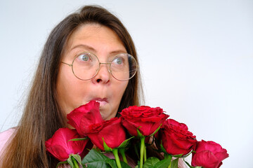 bouquet of flowers, red roses, middle-aged woman in round glasses 50 years with bulging eyes from bewilderment and surprise old, flower pollen allergy, close-up emotional female portrait