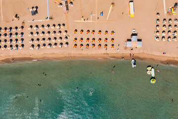 Concept of summer vacation. View from above, stunning aerial view of an amazing beach with beach umbrellas and turquoise clear water. Top view on a sun lounger under an umbrella on the sandy beach