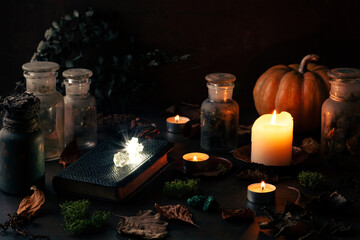 Witchcraft still life concept with potions, spell book, herbs ingredients candles and magical equipment