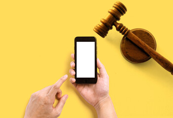 hand hold smartphone on yellow background with lawyer hammer for Copy space,concept online lawyer.