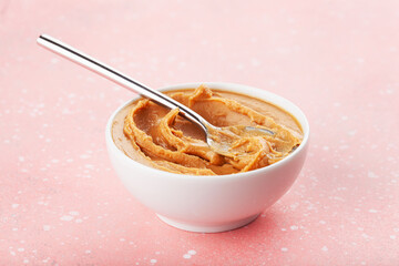 smooth peanut butter in bowl on pink background